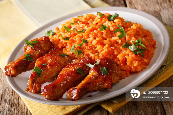 Authentic organic spicy Jollof rice with fried chicken wings close-up on a plate. horizontal