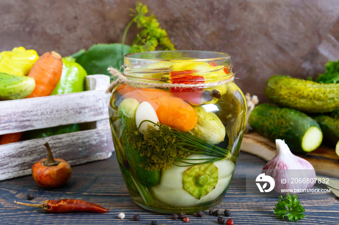 Marinated vegetables in a glass jar. Assorted cucumbers, peppers, carrots, patissons, zucchini. Pickles.