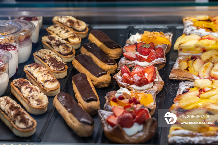 Delicious puffy chocolate eclair and strawberry tart in patisserie store