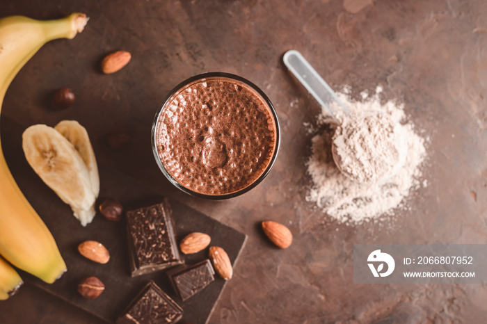 Chocolate milkshake smoothie with banana, protein and nuts on dark background, top view