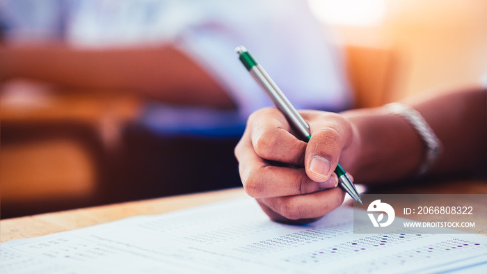 Hand of students writing and taking exam with stress in classroom