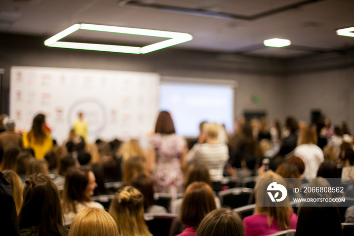 Abstract blurred photo of conference hall or seminar room with speakers on the stage and attendee background, seminar and study concept. Speaker on the podium. People at the conference hall.