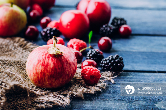 Food Background. Summer and Autumn fresh berries and fruits on blue wooden table background. Copy space. Top view delicious Vegan food - raspberry, blackberry, cherry apples and plums. Rustic style