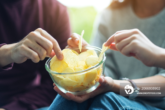 Closeup image of friends sharing and eating potato chips at home party