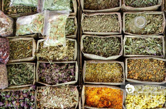 Containers with dried medicinal herbs for sale on the market. Healing herbs. Alternative medicine concept