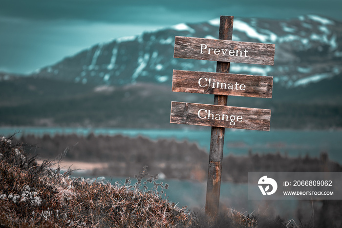 prevent climate change text quote engraved on wooden signpost outdoors in landscape looking polluted and apocalyptic.