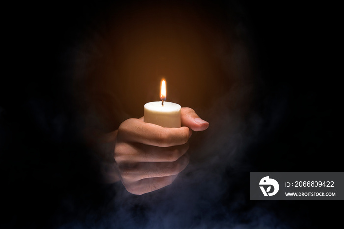 Hands holding candle over dark background