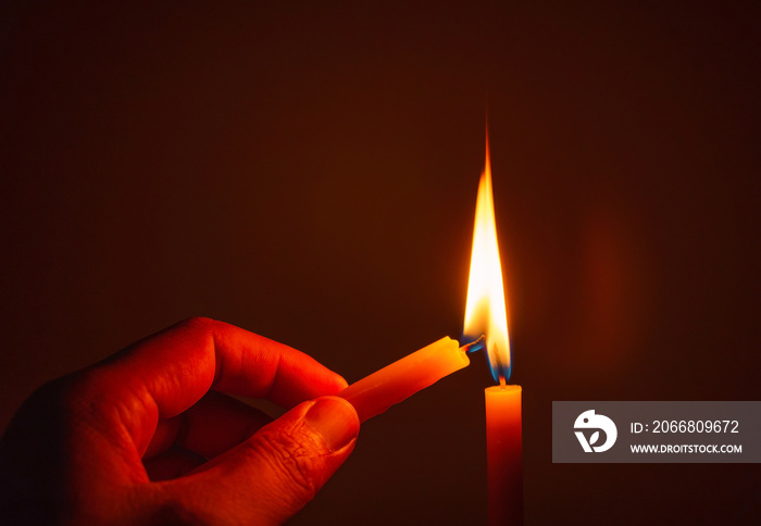 People’s hands are lit by candles in the dark. Design for the background, hand with candle, lighting candles, Burning candle on black background, Candle in hand, candle in the dark.