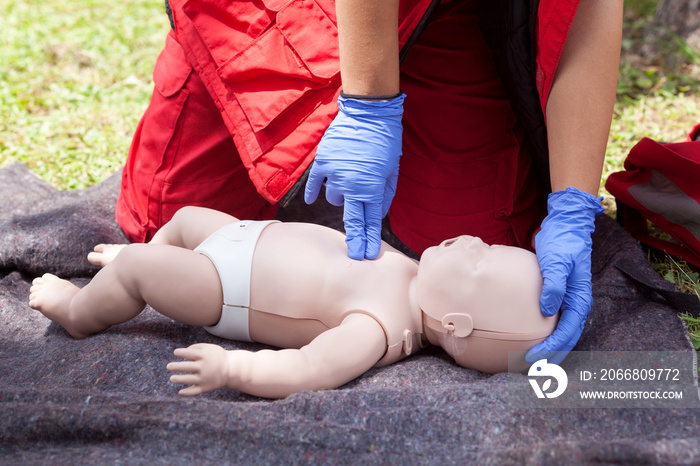 Paramedic performing CPR on baby dummy with two-finger chest compression