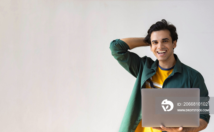 Portrait of happy male student with laptop looking at camera and smiling, copy space