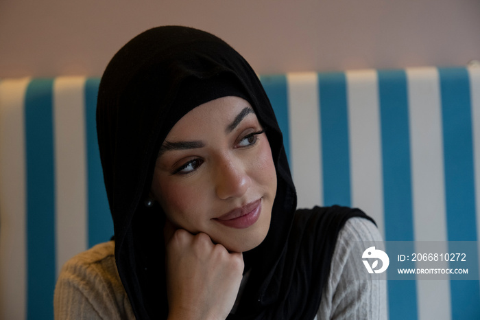 Young woman in hijab sitting in cafe