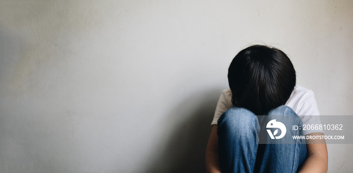 boy sitting with his hands on his knees with depression and sadness with copy space, Problems of domestic violence and bullying