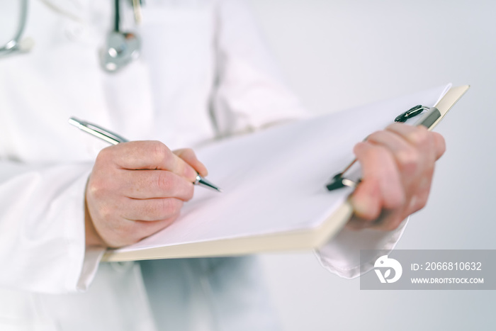 Female doctor in white uniform writing on clipboard paper