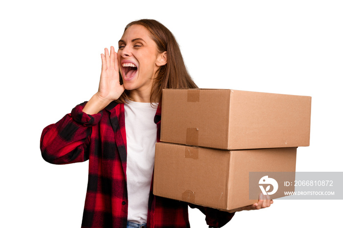 Young caucasian woman moving while picking up a box full of things isolated shouting and holding palm near opened mouth.