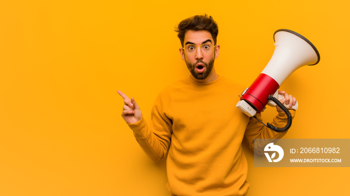 Young man holding a megaphone pointing to the side