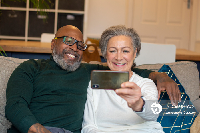 Senior couple using smart phone at home