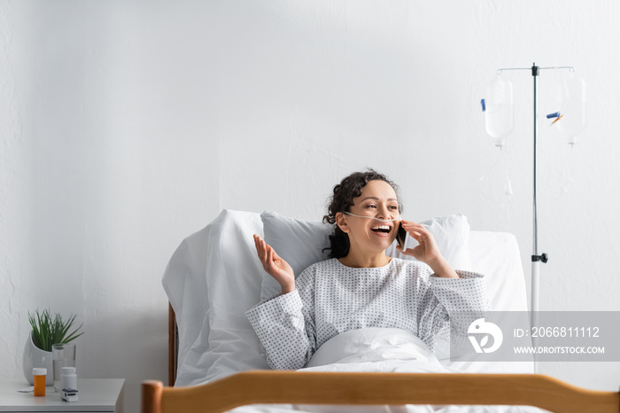 cheerful african american woman talking on mobile phone in clinic