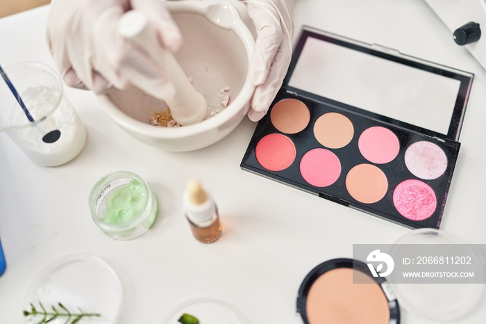 Young hispanic woman scientist making makeup working at laboratory