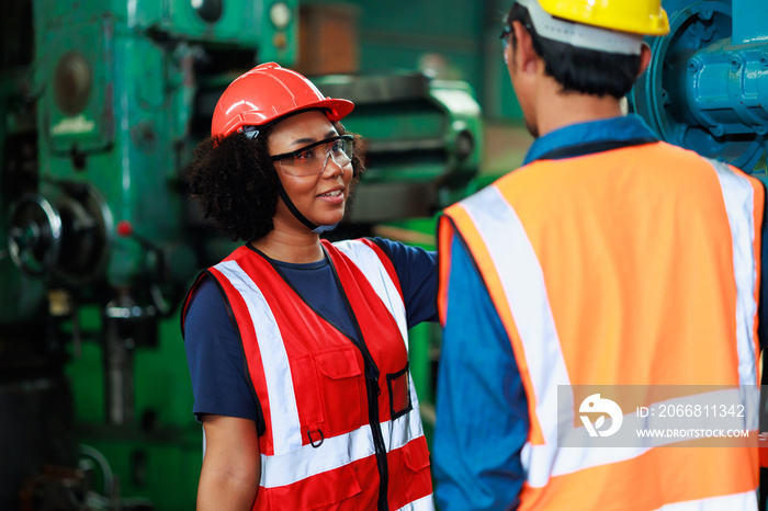 Black Woman worker wearing safety goggles control lathe machine to drill components. Metal lathe industrial manufacturing factory. Team work