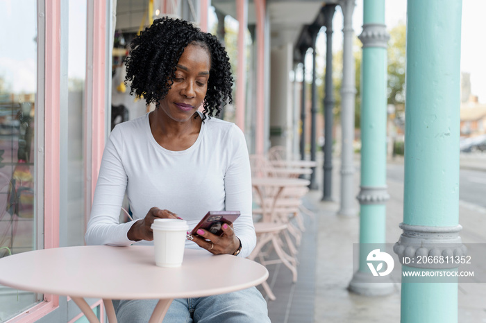 Woman using smart phone during coffee break in sidewalk cafe