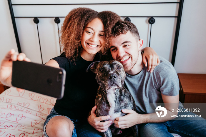 happy couple in love at home. Afro american woman, caucasian man and their pit bull dog together. Family concept