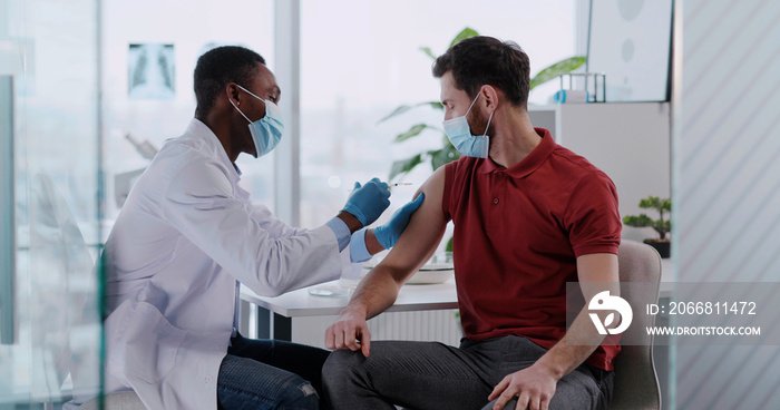 African american doctor servicing male custome rin private clinic hospital doing vaccination injection against flu influenza.