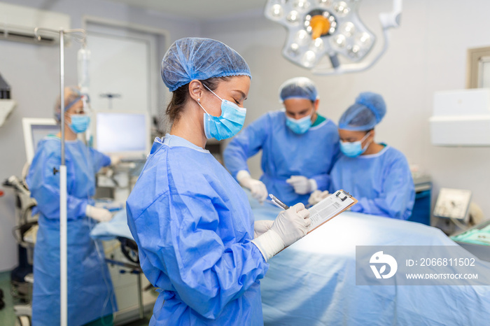 Surgeon writing on clipboard in operation room, anaesthesiologist writing the updates