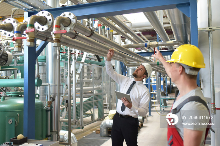 businessman and worker meeting in a factory - maintenance and repair of the industrial plant