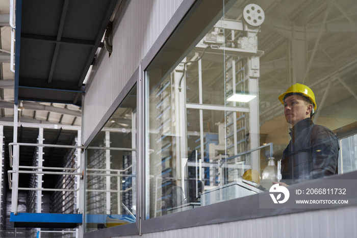 Engineer worker at control room. Portrait of a young technician worker in a factory. The operator monitors the work process from control room