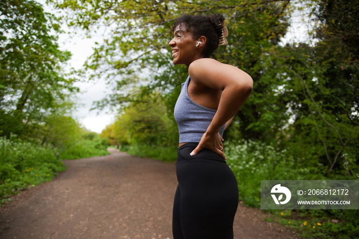 Young curvy woman with vitiligo working out in the park wearing earbuds