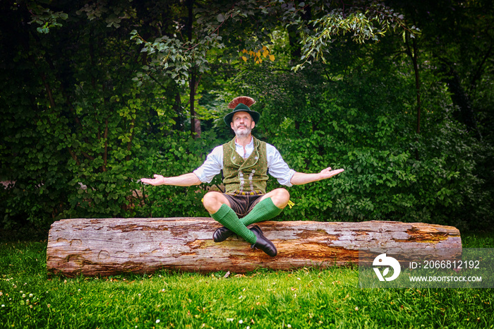 bavarian man sitting on tree stump and meditating