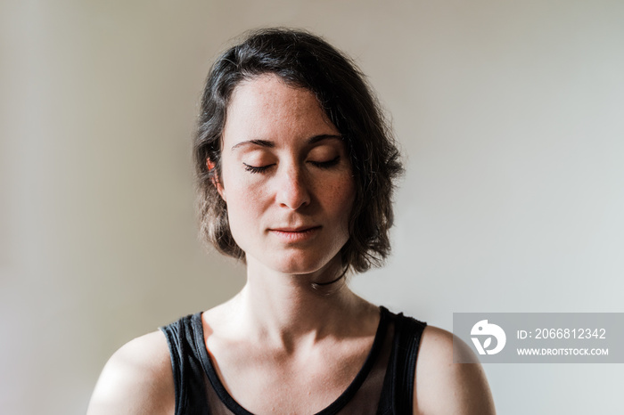 Hispanic woman doing yoga meditation indoor at home - Focus on face