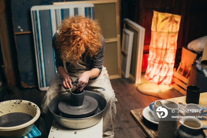 woman making pottery on rolling wheel indoor