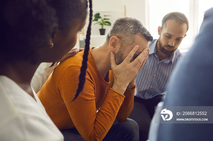 Honest conversation in group therapy. Diverse people comforting upset mature patient helping him deal with grief and other problems. Alcohol addict hides face ashamed of what he has done with his life