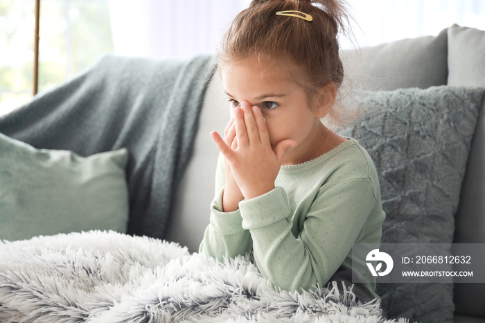 Sick little girl sitting on sofa at home