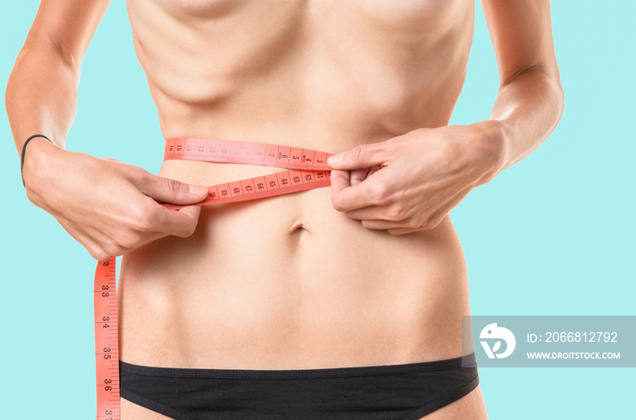 Underweight young woman measuring her waist