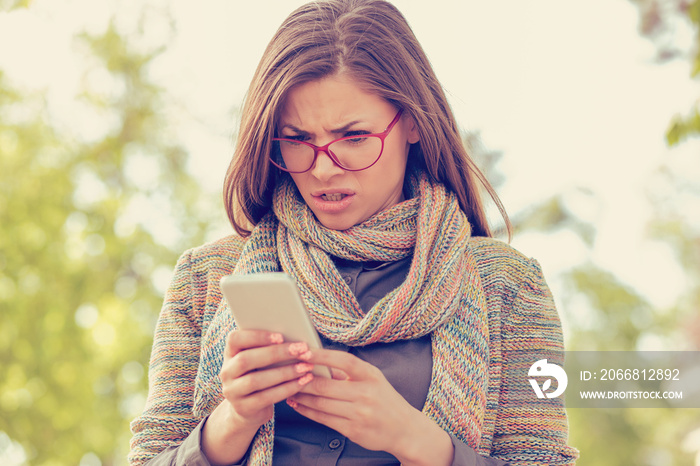 Young woman looking angry at the phone