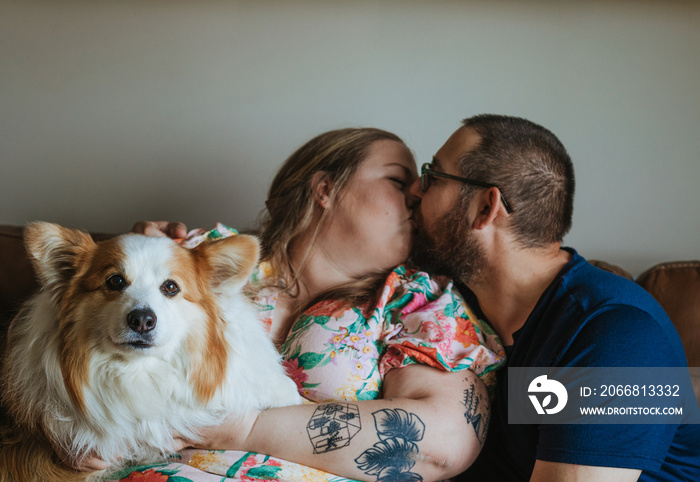 woman and man kiss while holding dog