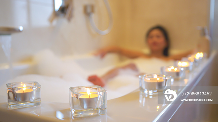 Lined up glowing candles for relaxing atmosphere while taking a nice bubble bath