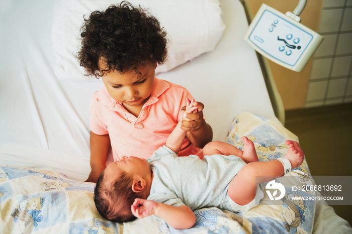 First meeting of adorable african toddler boy and his newborn brother in a prenatal hospital