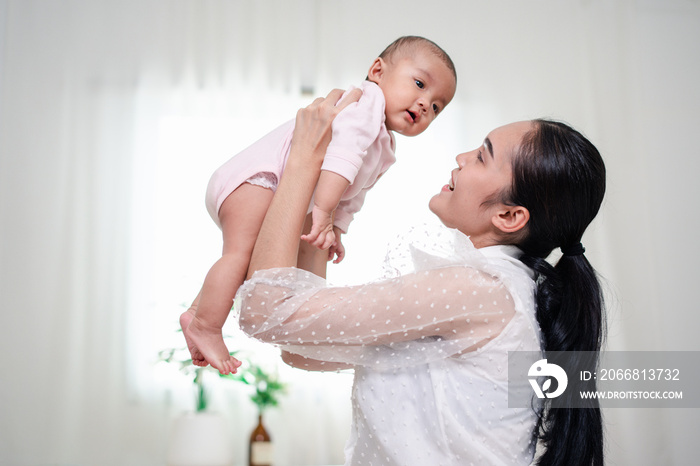 Mother Parenting and newborn birth life. Mom and baby boy playing in sunny bedroom, Family having fun together. childcare, maternity concept.