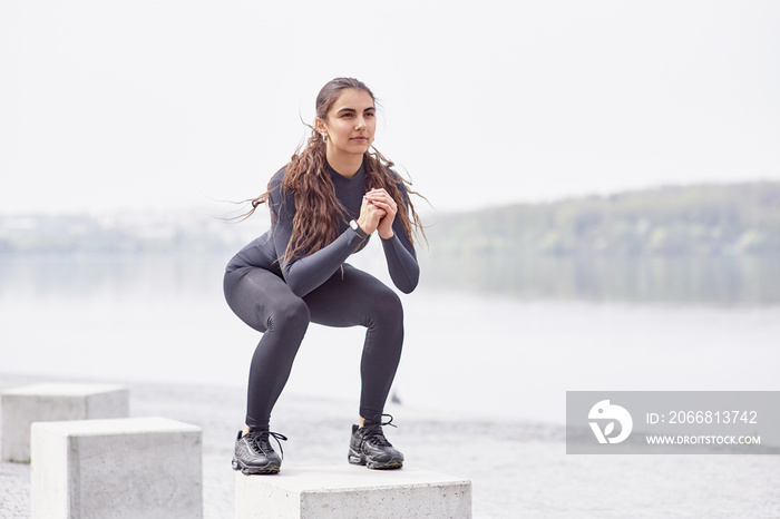 Fitness sport women in fashion sportswear doing yoga fitness exercise in the city street over gray concrete background on the coast