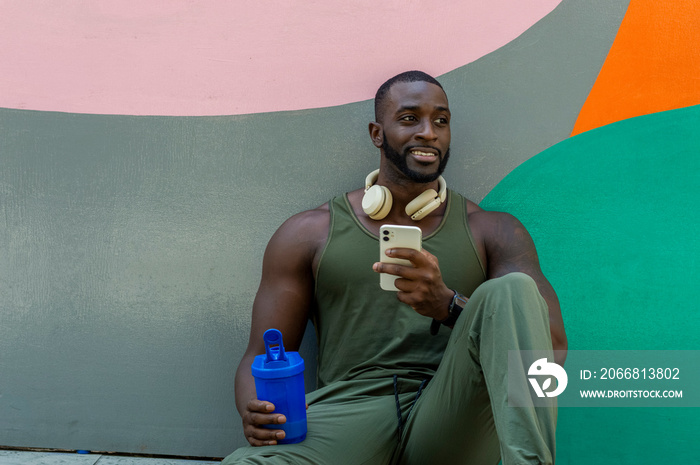 Mid adult man holding phone and plastic water container