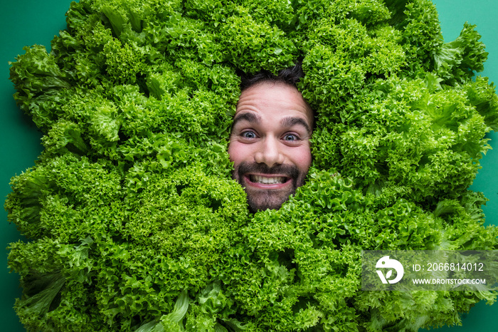 Men with salad ,concept for food industry. Face of laughing man in salad surface..