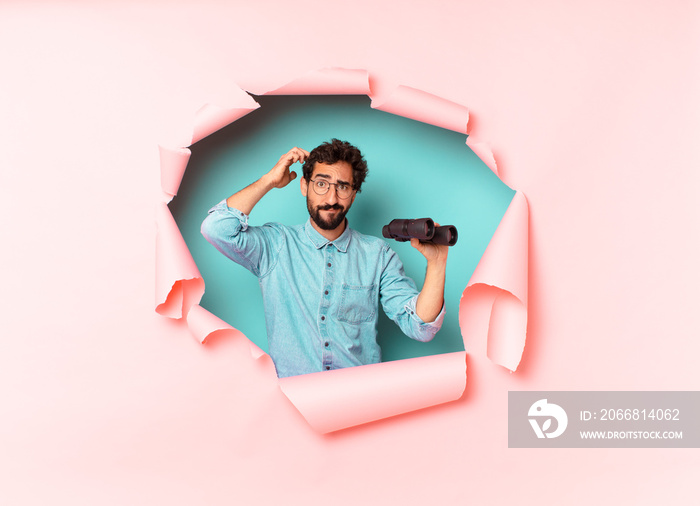 young crazy bearded man. thinking or doubting expression. binoculars concept