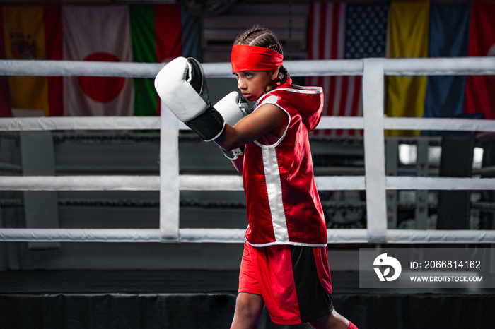 Kids sport concept. Girl sportsman muay thai boxer fighting in gloves in boxing gym.