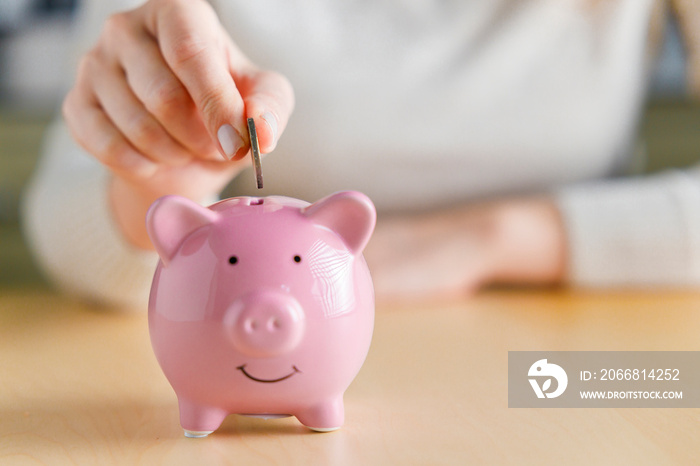 Woman putting money into piggy bank. Concept of money saving and budgeting..