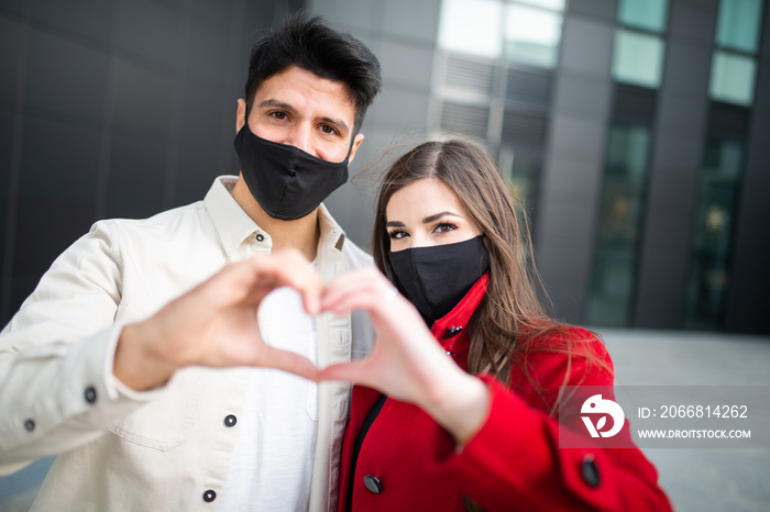 Couple wearing masks and doing the heart sign with their hands, covid and coronavirus love concept