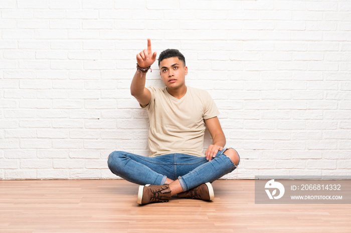 Young man sitting on the floor touching on transparent screen