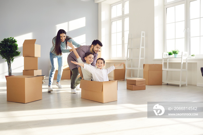 Family with children having fun in new home. Joyful first-time buyers with kids playing with boxes in living room. Real estate, residential mortgage, moving into dream house, happy future concept